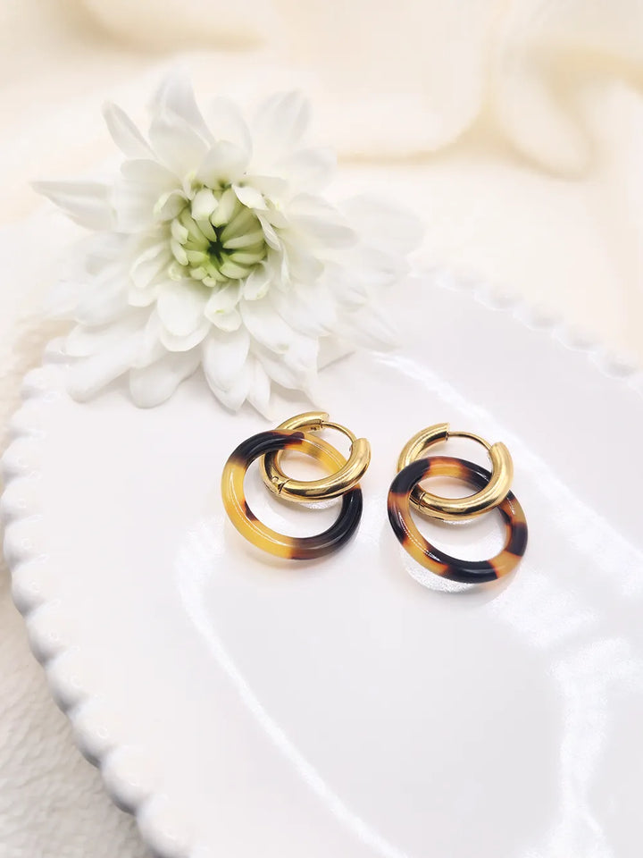 Détail créoles entrelacées résine ambre et acier doré