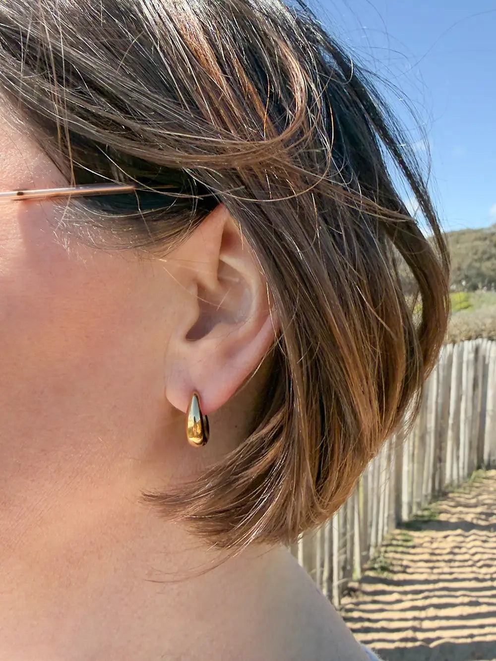 Femme portant des boucles d’oreilles dorées bombées 