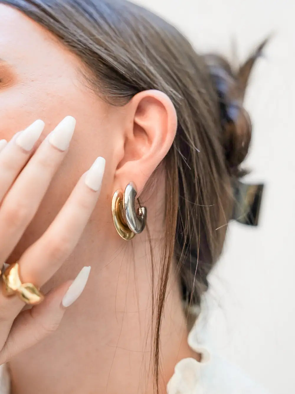 femme portant des boucles d'oreilles en forme de créoles plates et larges de couleur doré et argenté