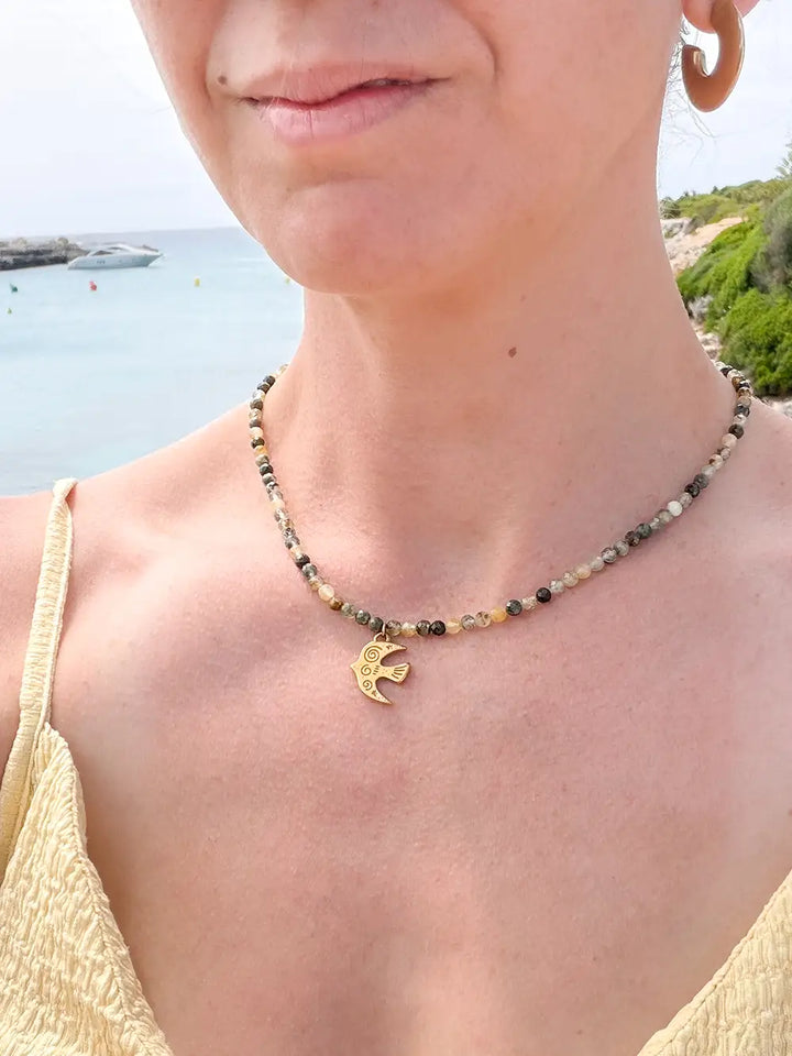 femme portant un collier en pierres naturelles olivines avec pendentif oiseau gravé