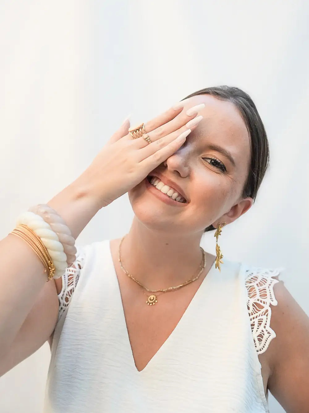 femme avec parure de bijoux bohème doré, rose poudrée et blanc.